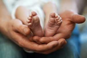 Dad holds in his hands small baby foot